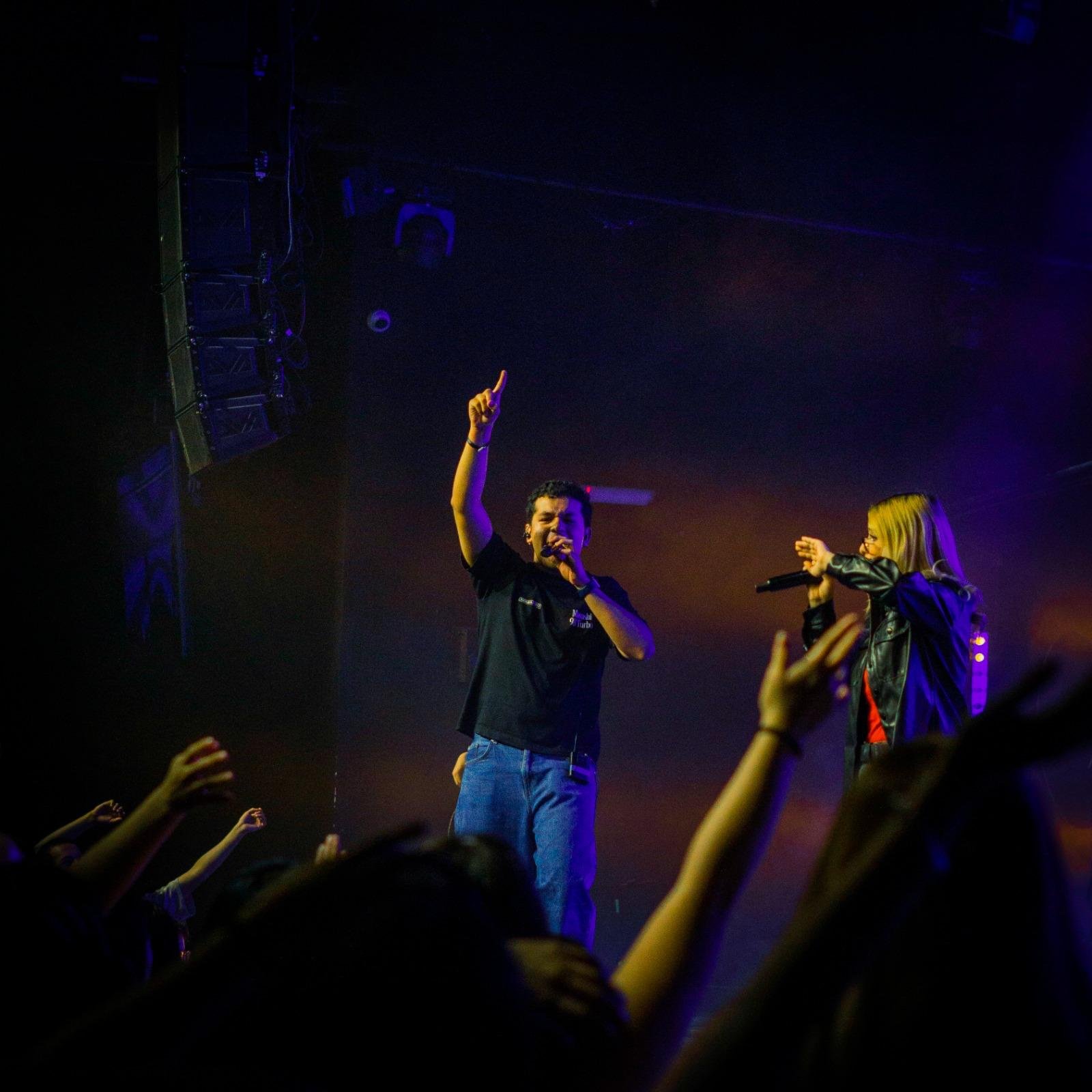 Cantantes en el escenario y manos alzadas en la congregación