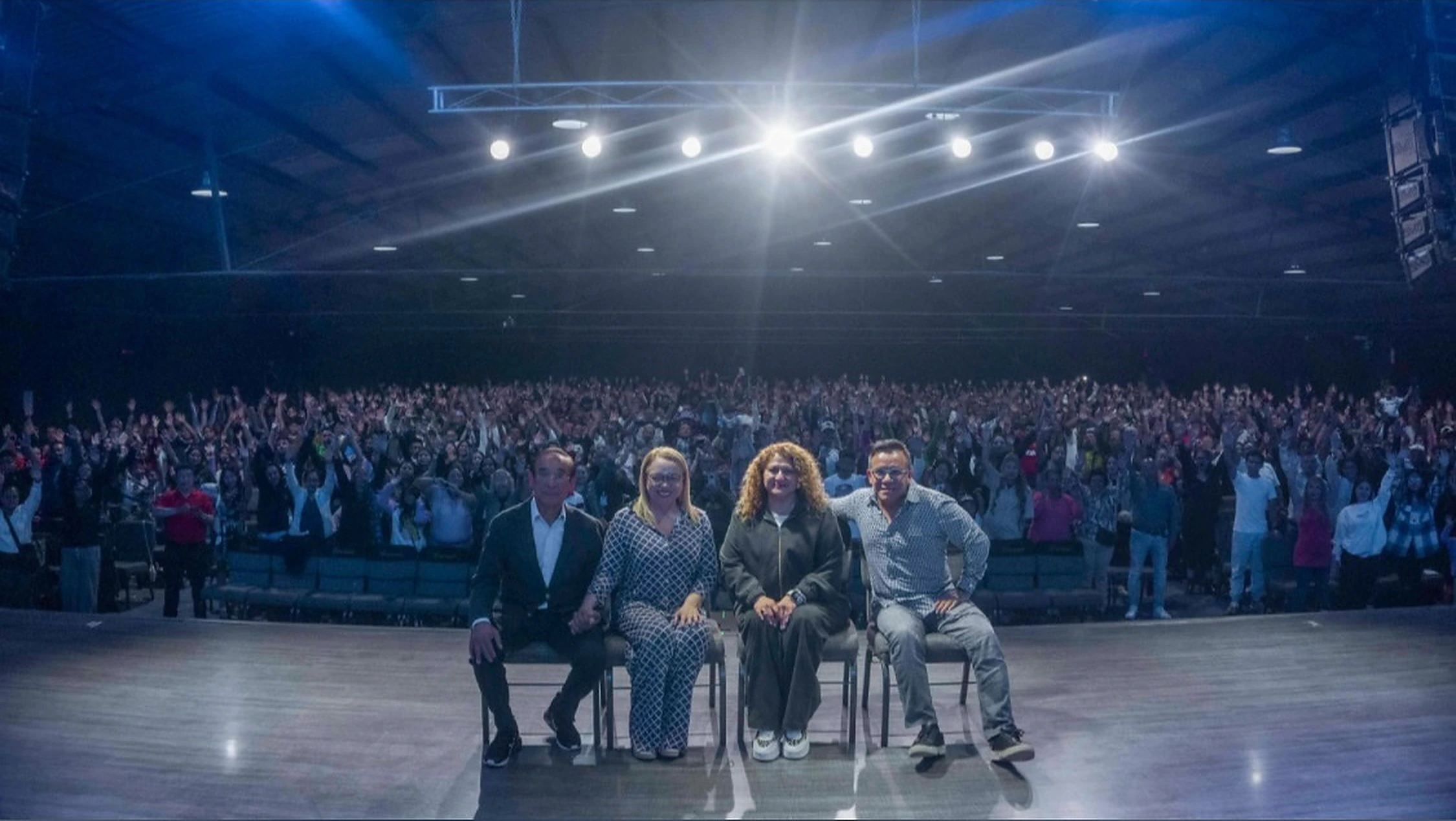 Cuatro personas frente a la comunidad reunida en el auditorio de Soplo de Vida